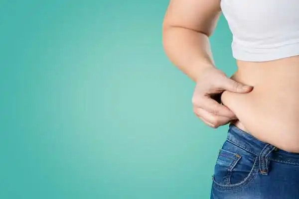 Image of woman pinching her love handles to show weight gain Kingshurst